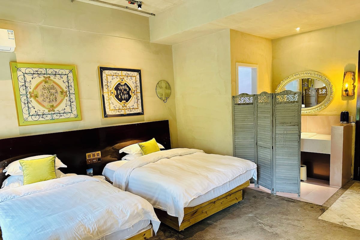 Una habitación de hotel con dos camas, un espejo grande, un armario y una mesita de noche pequeña.