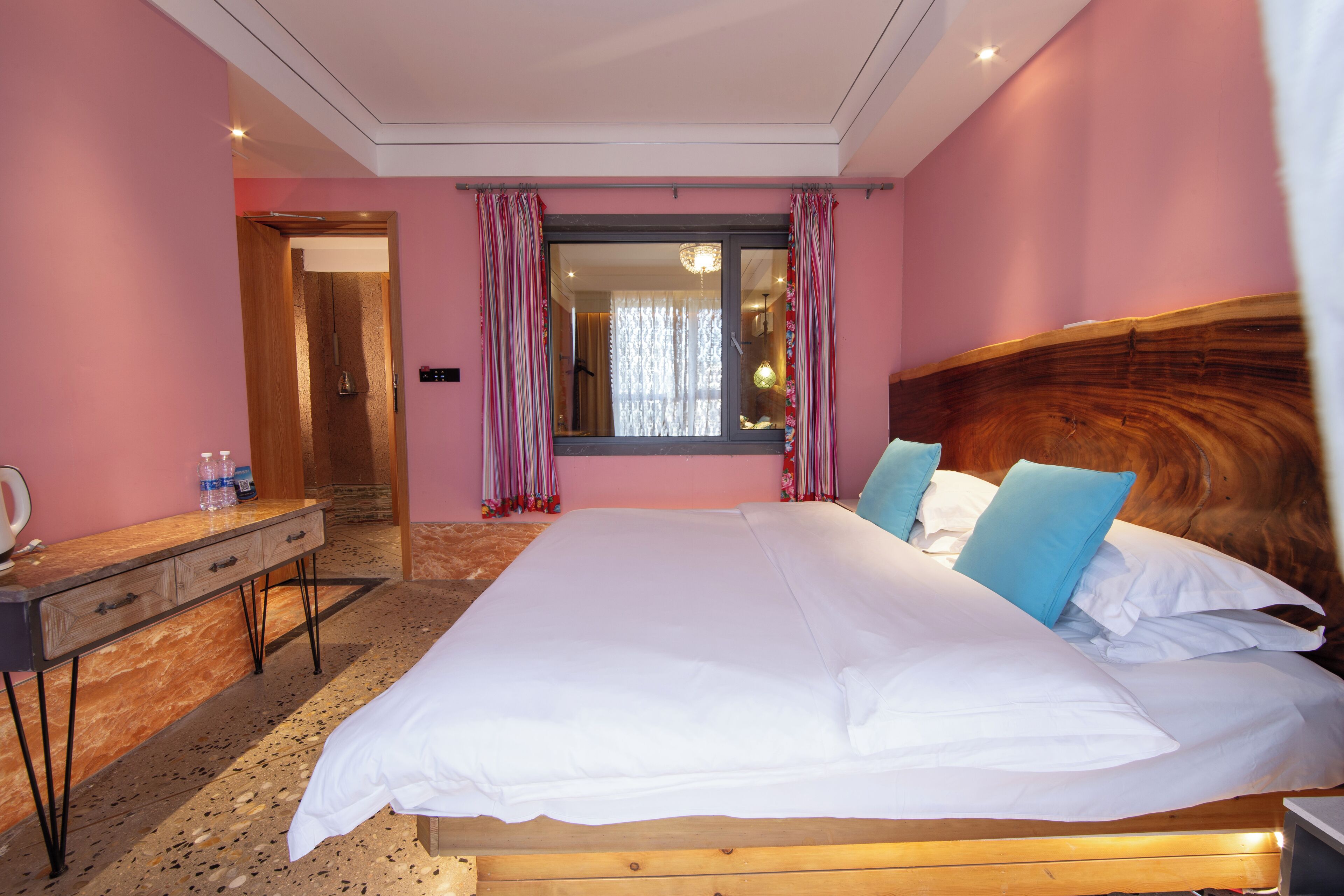 A bedroom with a large bed, a wooden headboard, a bedside table, and a mirror.