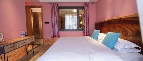 A bedroom with a large bed, a wooden headboard, a bedside table, and a mirror.
