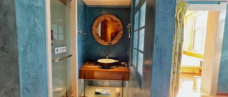 Un baño con lavamanos, espejo y toallero.