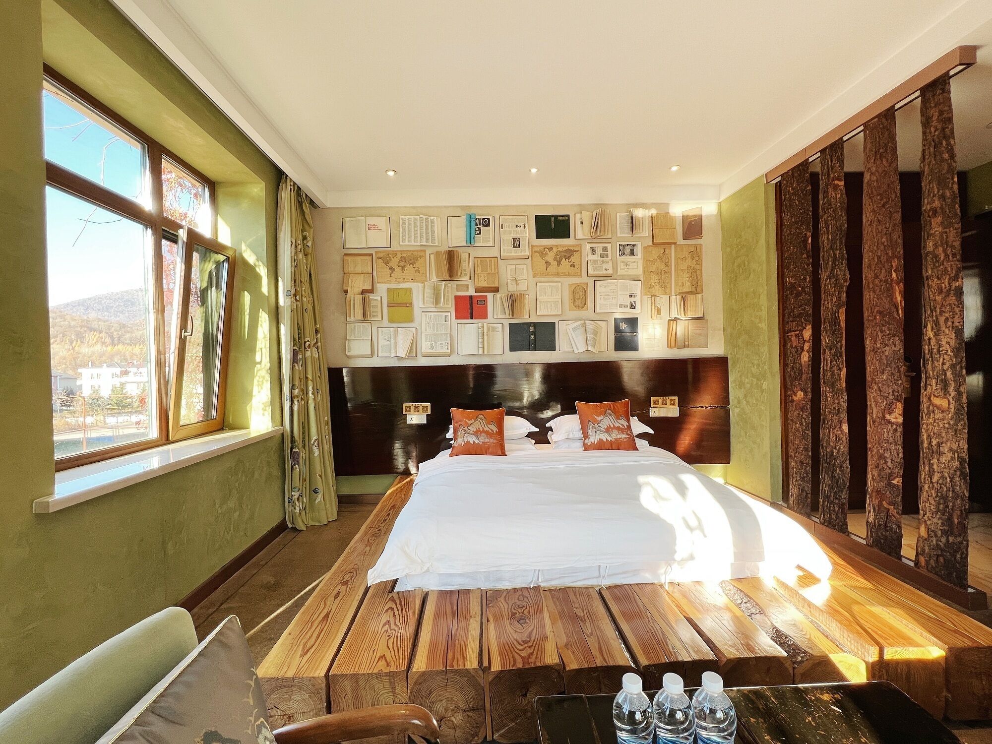 A hotel room with a large bed, wooden headboard, and a wall decorated with various framed items.
