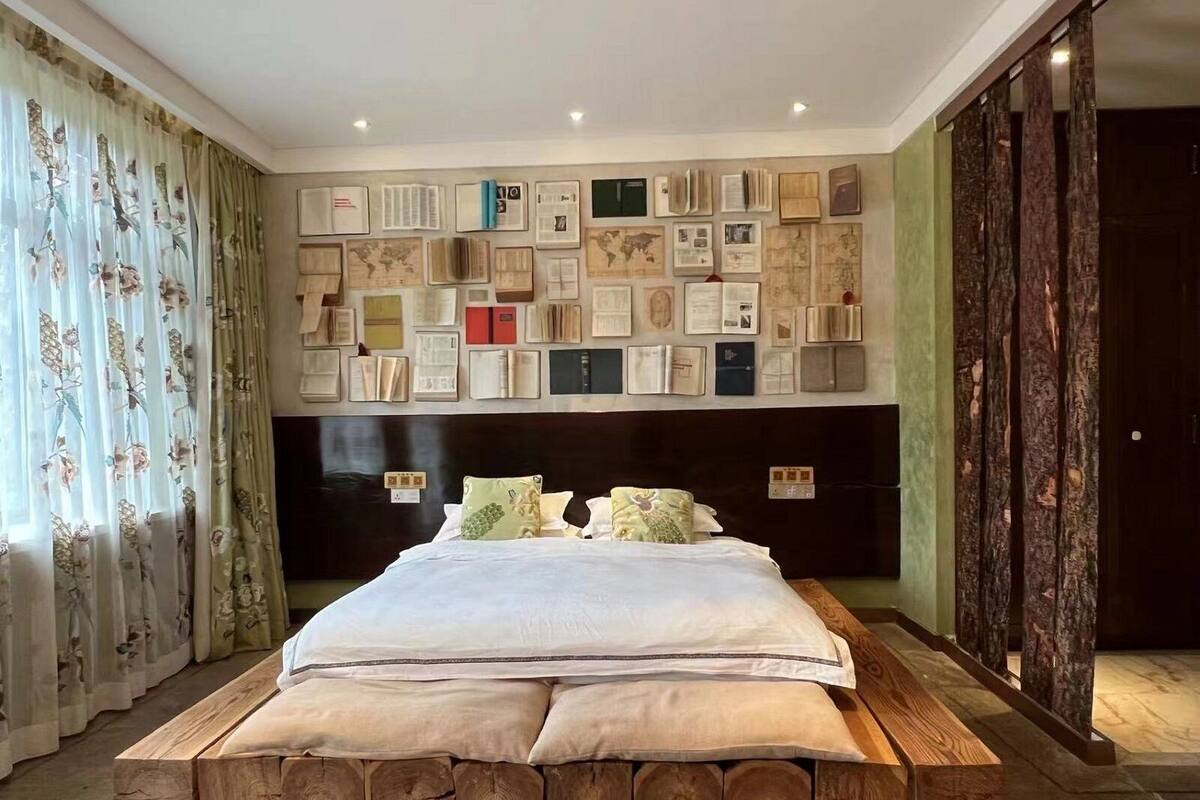Un dormitorio con una cama grande, cortinas florales y una pared decorada con varios objetos enmarcados.