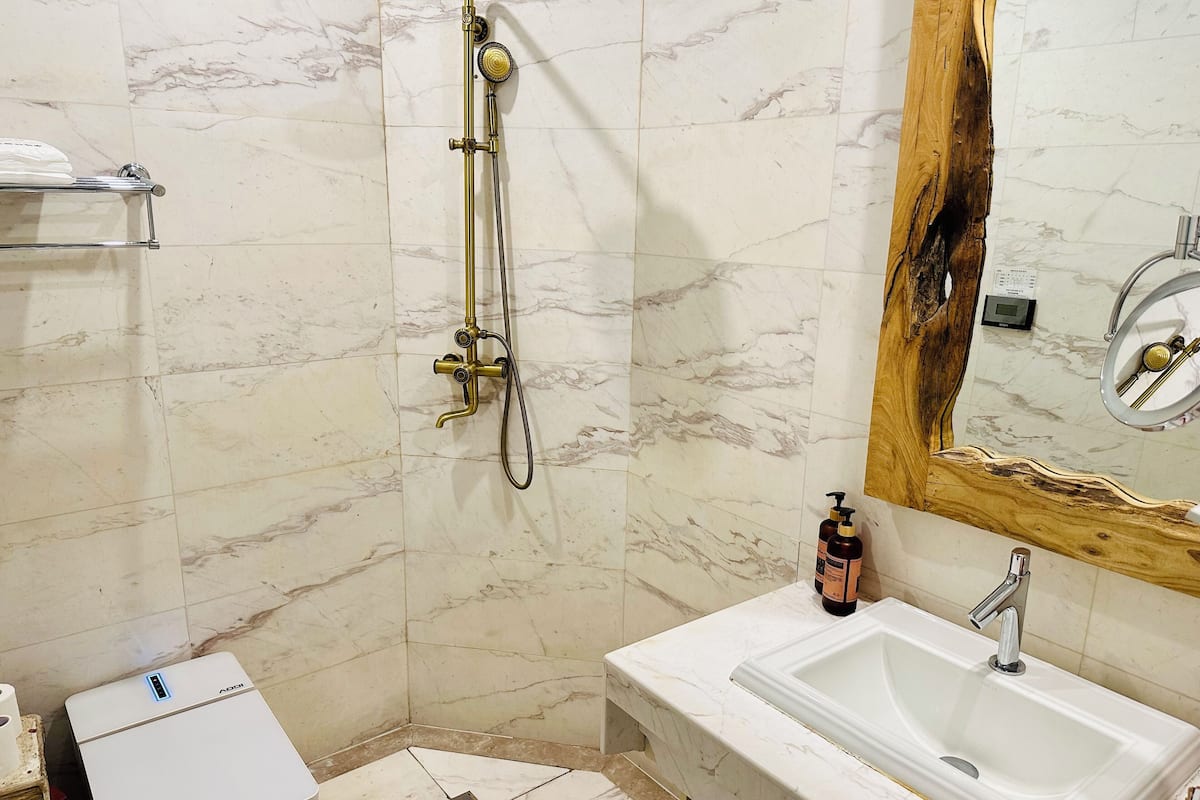 Un baño con ducha, lavamanos y espejo de marco de madera.