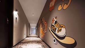 A hallway with a patterned carpet, a wall-mounted light, and a large mural of a shoe. - Merica Hotel -Chengdu Chunxi Road (Chengdu)