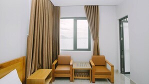 A room with a bed, two chairs, a small table, and a window with curtains.
