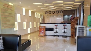 A hotel reception area with a modern design, featuring a reception desk, two bar stools, and a decorative statue.