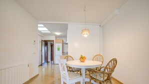 A dining area with a round table, white chairs, and a fruit bowl. - Comtat Muro 2 by Rentallorca (Muro)