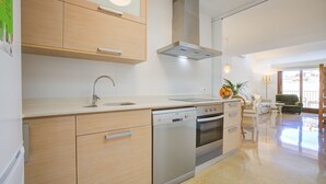 A modern kitchen with wooden cabinets, stainless steel appliances, and a large window. - Comtat Muro 2 by Rentallorca (Muro)