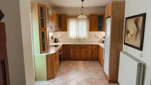 A kitchen with wooden cabinets, a tiled floor, a hanging light fixture, and a radiator.