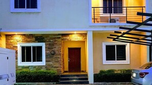 A two-story house with a stone facade, a wooden door, and a staircase leading to the upper floor. - NiCotel Apartments (Abuja)