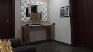 A modern reception area with a geometric patterned wall, a central mirror, and a framed picture. - NiCotel Apartments (Abuja)
