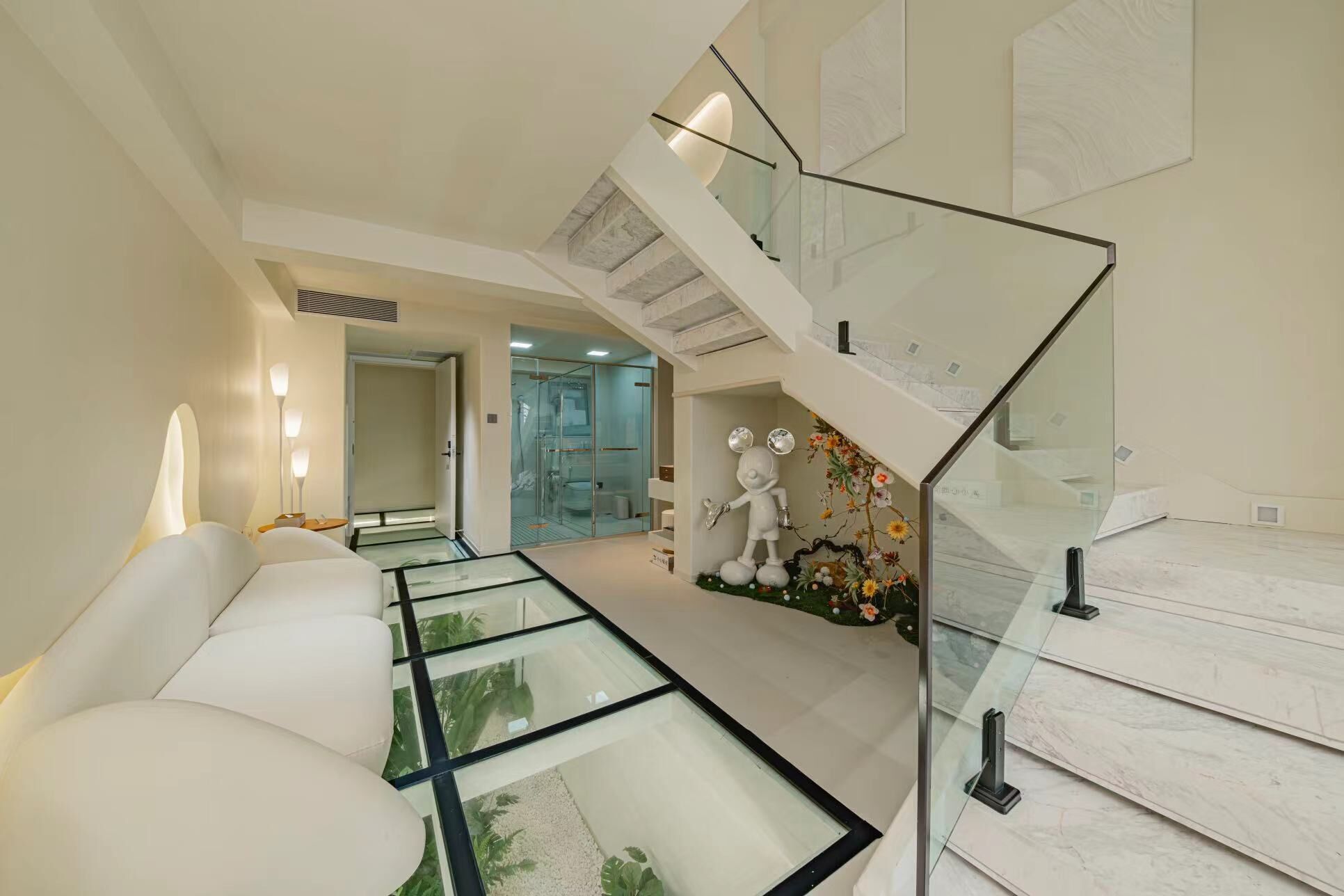 A modern hotel lobby with a glass staircase, a reception desk, and a seating area with a glass table.