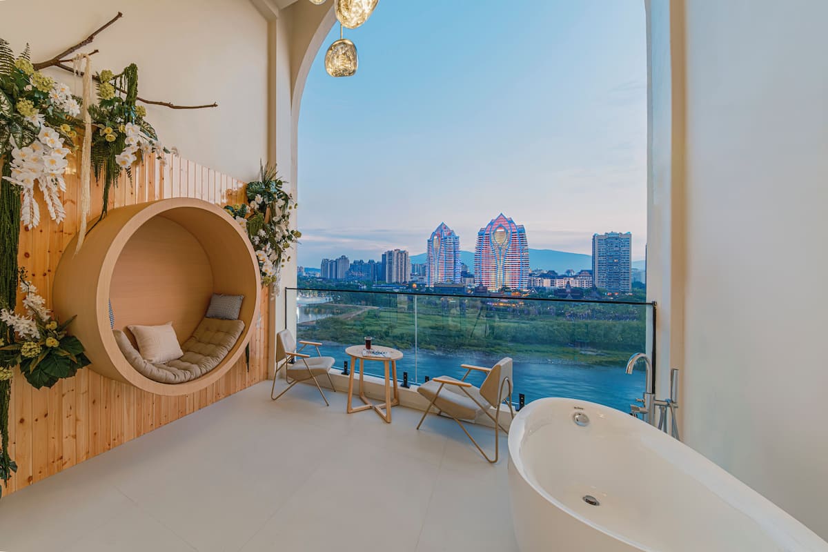 Une salle de bain moderne dotée d’une grande baignoire, d’un espace salon circulaire offrant une vue sur le paysage urbain et la rivière.