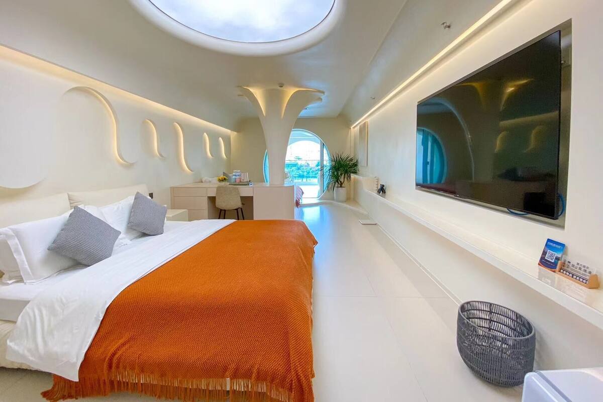 Une chambre d’hôtel moderne dotée d’un grand lit, d’un bureau, d’une télévision et d’une lucarne.