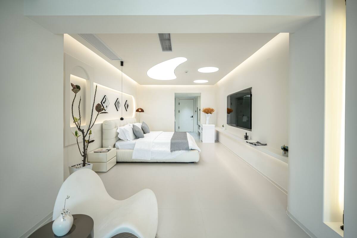 Une chambre moderne avec un lit, des tables de chevet, un miroir et un téléviseur.