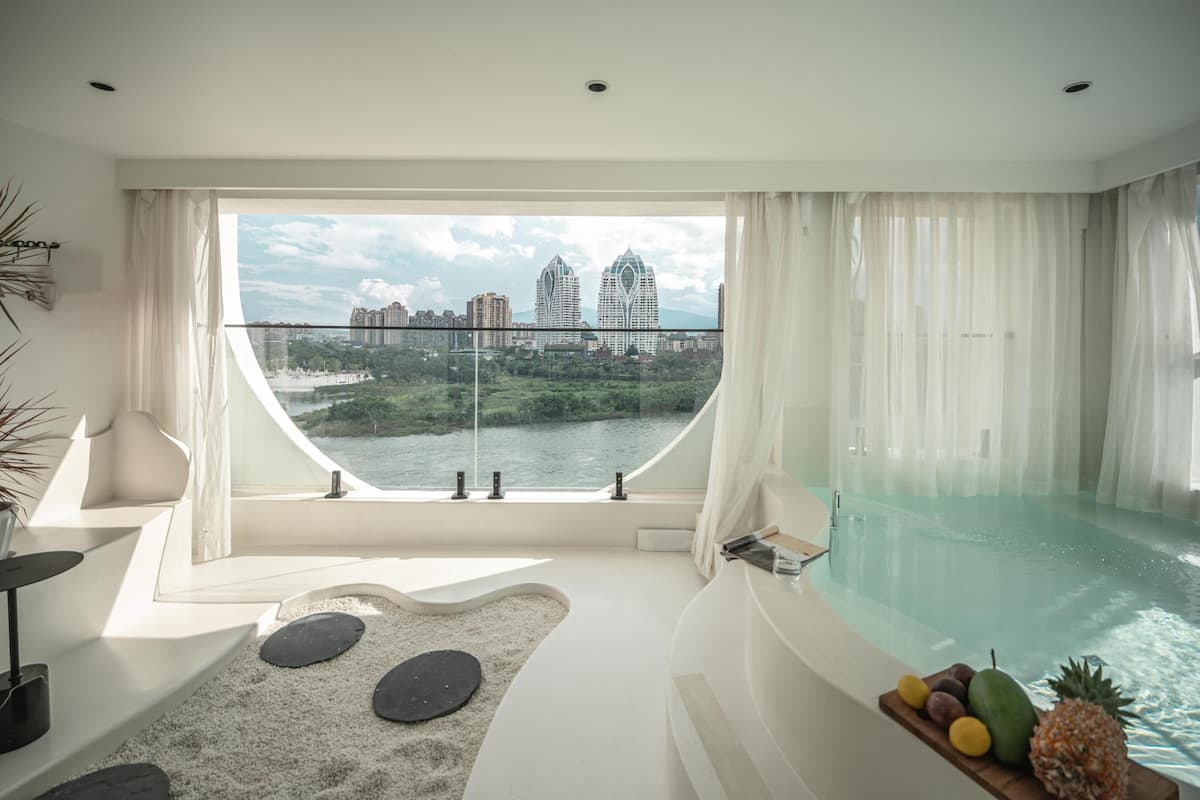 Une salle de bain moderne avec une grande baignoire, une vue sur le paysage urbain et un petit espace piscine.