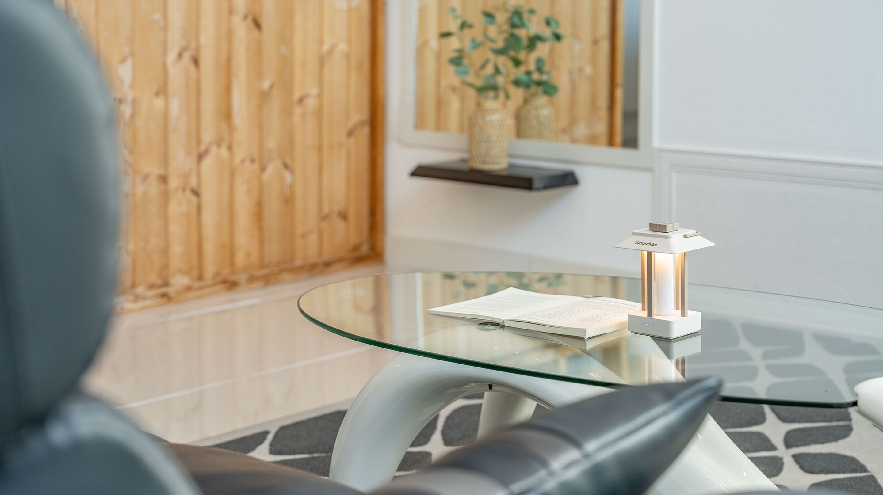 A modern interior with a glass table, a book, and a lamp.