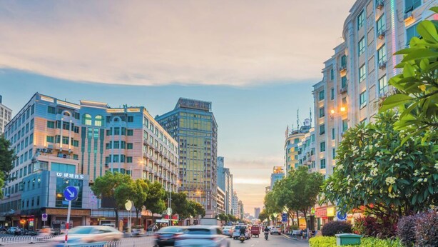 A city street lined with multi-story buildings, some with commercial signage. - Huadu Hotel (Quanzhou)