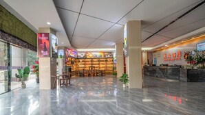 Um saguão de hotel com balcão de recepção, área de estar e bar.