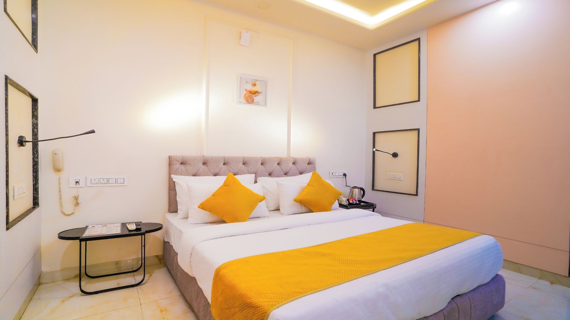 A hotel room with a bed, bedside table, and a wall-mounted phone.