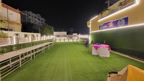 Een evenementenruimte buiten met kunstgras, tafels, stoelen en een podium.
