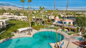 A resort with a large pool, palm trees, and mountain views.