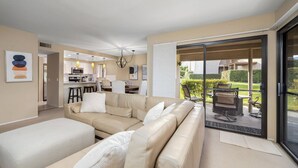 A modern living room with a beige sofa, a dining area, and a kitchen in the background.