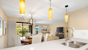 A modern kitchen with a large island, stainless steel sink, and pendant lighting.
