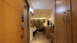 A hotel room with a wooden floor, a bed, a desk, a chair, a lamp, and a wardrobe. - Hotel Aashray Inn  (Hubli)