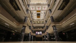 A multi-level atrium with a central open space, multiple floors, and a large digital display at the bottom.