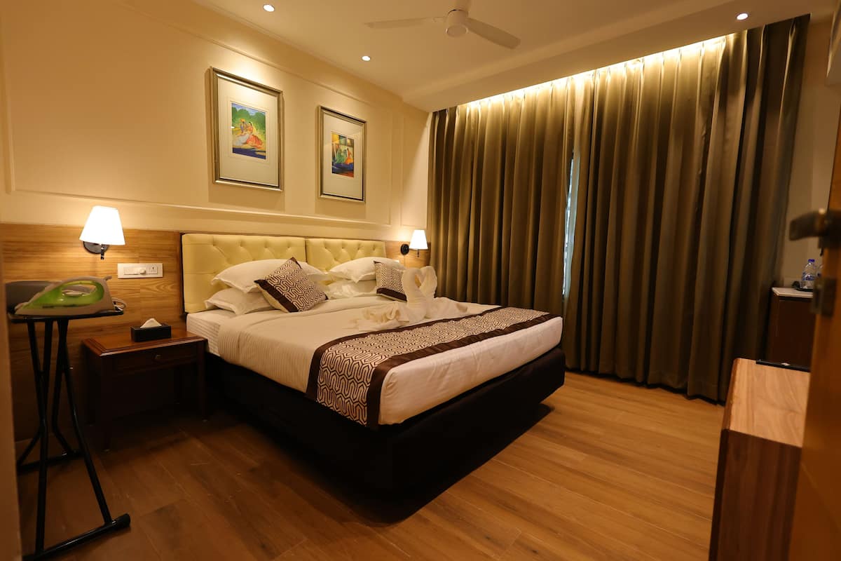 A hotel room with a large bed, two bedside lamps, a ceiling fan, and two framed artworks on the wall.