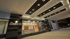 A modern hotel entrance with a prominent sign for Aashray Inn, featuring a geometric ceiling design and a glass facade. - Hotel Aashray Inn  (Hubli)