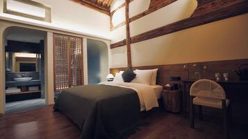 Un dormitorio con una cama grande, vigas de madera, un escritorio pequeño y una silla.