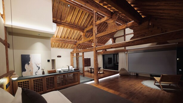 Una habitación amplia con techo de madera, una cama grande, un escritorio de madera y un ventanal.