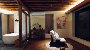Un baño moderno con una bañera independiente, suelo de madera y un ventanal grande.