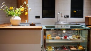 Una cocina moderna con encimera de madera, un florero con flores y una vitrina de vidrio con varios postres.