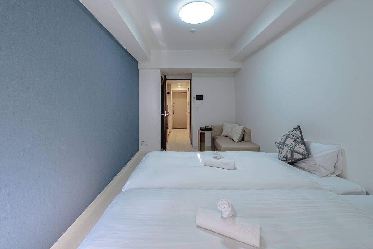 Une chambre d’hôtel avec deux lits, une petite table et un canapé.