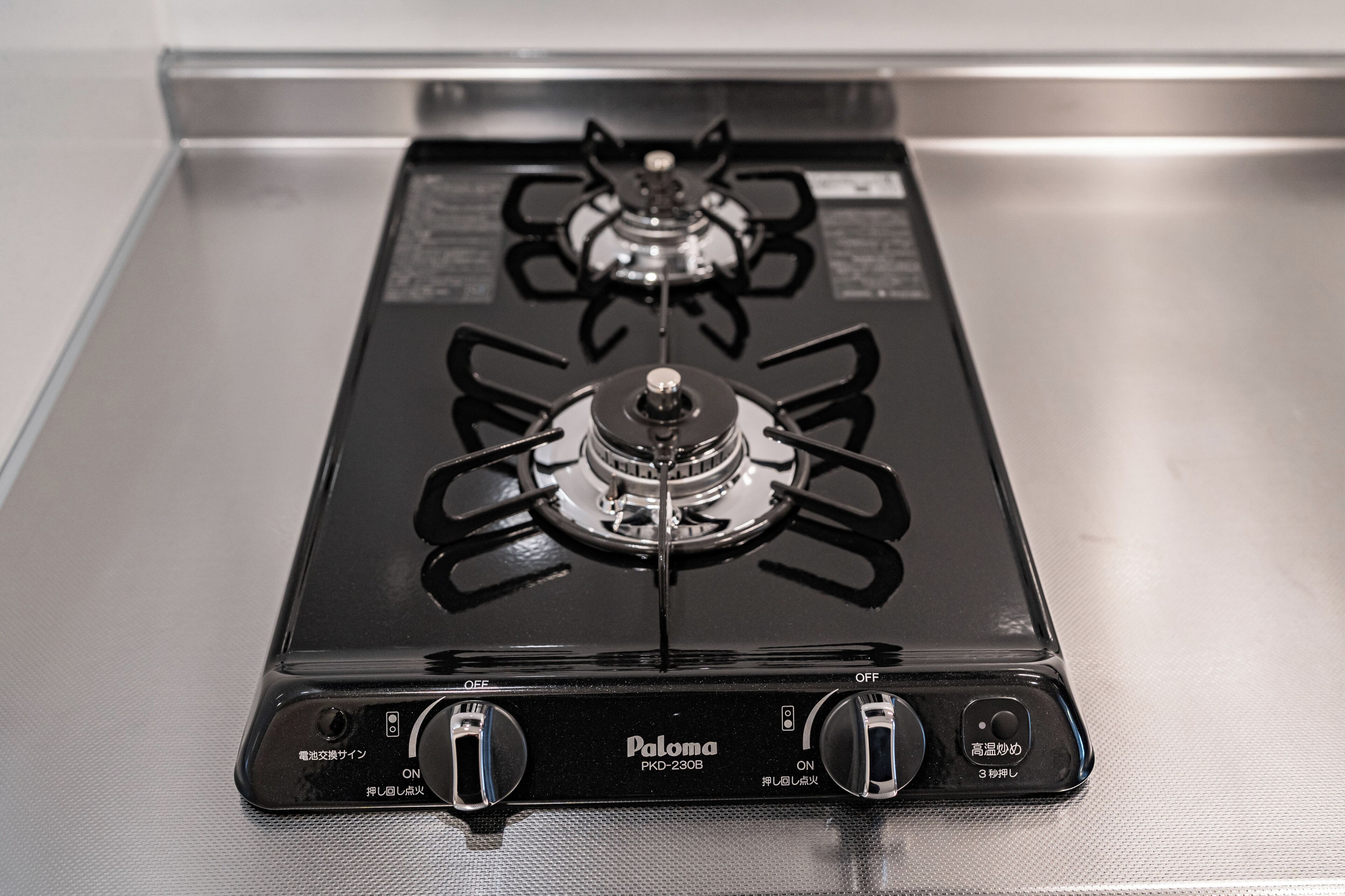 A black gas stove with four burners and two control knobs.
