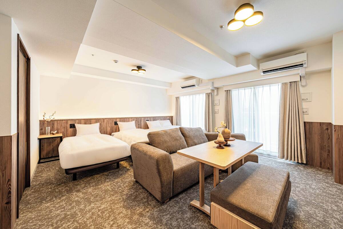 Une chambre d’hôtel avec un lit, un canapé, une table et un petit bureau.