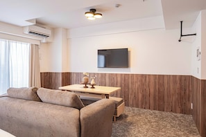 Uma sala de estar moderna com um sofá, uma parede de destaque em madeira, uma TV de tela plana e um lustre.