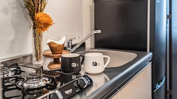 A kitchen with a gas stove, two coffee mugs, a vase with flowers, and a toaster.