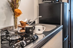 A kitchen with a gas stove, two coffee mugs, a vase with flowers, and a toaster.