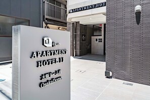 Placa para 'APARTMENT HOTEL II OsakaDome' com design moderno.