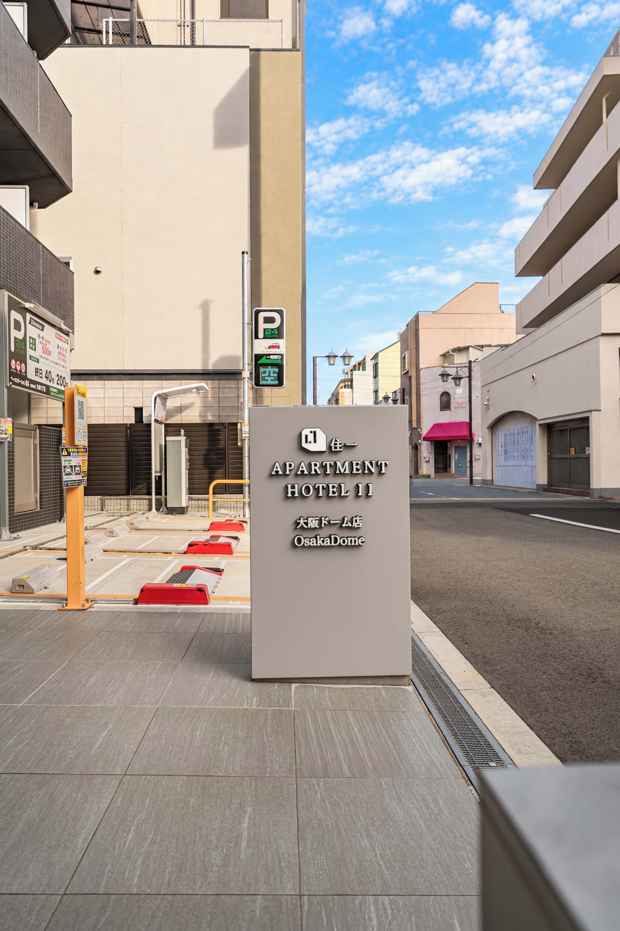 Señal para el 'APARTMENT HOTEL 11', con un letrero de estacionamiento 24 horas y un código QR.
