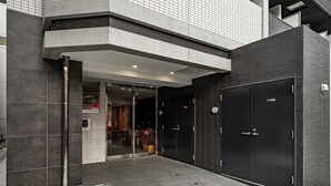 Ingresso di un edificio moderno con porta in vetro, tubo antincendio in metallo e parete in mattoni.