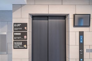 Een lift met een digitaal display, een rookmelder en een bordje 'niet roken'.