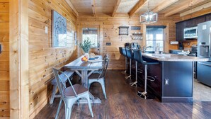 A wooden cabin interior with a dining area, bar, and kitchen. - Hot Tub + Game Loft | Located in Douglas Lake Resort | Mountains are Calling (Sevierville)