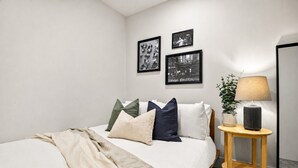 A bedroom with a bed, pillows, a bedside table with a lamp, and wall-mounted pictures.