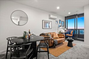 Relax in this stylish living area with a round dining table for two, a comfortable sofa, and a single armchair.