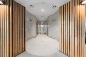 A modern bathroom with a curved floor, wooden panel walls, and a bench in the center.